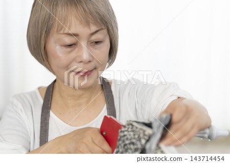 一位老婦人在客廳裡改造了一個娃娃椅,作為她的DIY愛好。 一位老婦人在客廳裡改造了一個娃娃椅,作為她的DIY愛好。 143714454