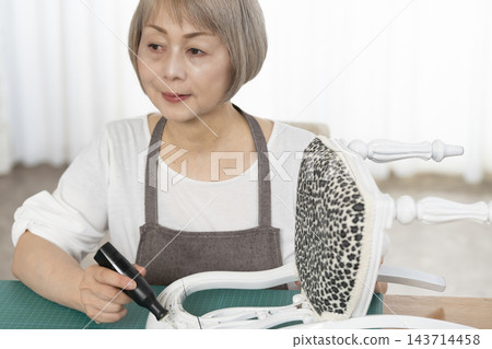 一位老婦人在客廳裡改造了一個娃娃椅，作為她的DIY愛好。 143714458