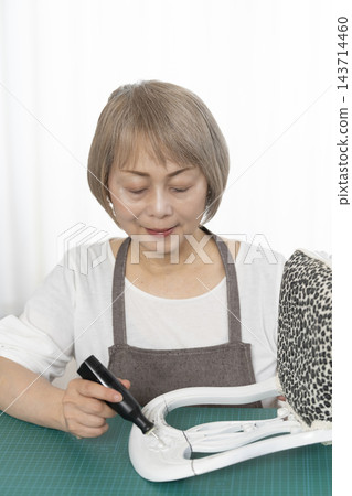 一位老婦人在客廳裡改造了一個娃娃椅，作為她的DIY愛好。 143714460