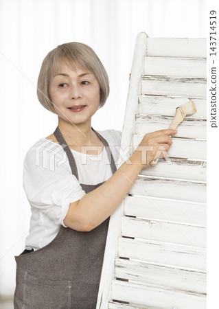 一位老婦人在客廳裡製作椅子,這是她的DIY愛好。 一位老婦人在客廳裡製作椅子,這是她的DIY愛好。 143714519