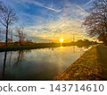 Beautiful sunset casting warm reflections over peaceful waterway with trees 143714610