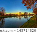 Peaceful river view featuring fall foliage and shimmering water 143714620