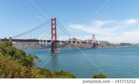 Golden Gate Bridge, San Francisco, California, USA, the red suspension bridge crossing the Golden Gate strait toward the Marin Headlands, framed by coastal shrubs Golden Gate Bridge, San Francisco, California, USA, the red suspension bridge crossing the Golden Gate strait toward the Marin Headlands, framed by coastal shrubs 143715252