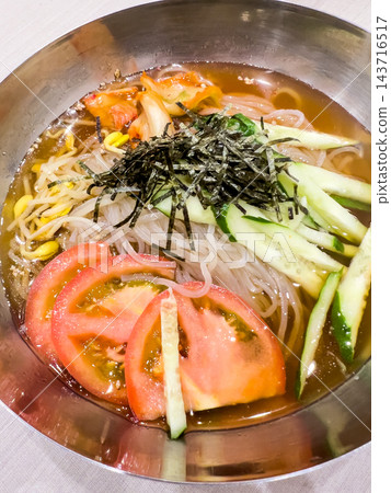 特寫鏡頭展現了清爽冰涼的韓國冷面,裡面鋪滿了各種食材。 特寫鏡頭展現了清爽冰涼的韓國冷面,裡面鋪滿了各種食材。 143716517