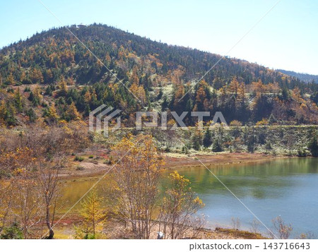 The Yumi Pond on Mount Kusatsu-Shirane, the mountain slopes dyed in autumn colors, and the plateau scenery with walking trails. The Yumi Pond on Mount Kusatsu-Shirane, the mountain slopes dyed in autumn colors, and the plateau scenery with walking trails. 143716643