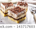 Delicious layered cakes with cream, bananas, and fluffy whipped cream served on an elegant plate. The top of the desserts is sprinkled with finely grated dark chocolate 143717603