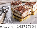 Delicious layered cakes with cream, bananas, and fluffy whipped cream served on an elegant plate. The top of the desserts is sprinkled with finely grated dark chocolate 143717604