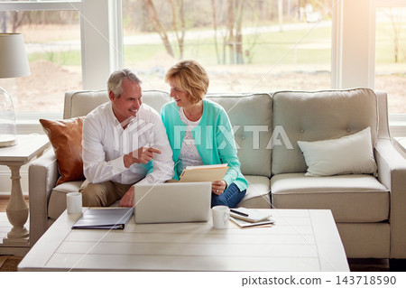 Senior couple, documents and laptop on couch with discussion, smile and point for taxes in home. Old man, woman and computer with paperwork for compliance, reading and investment report with solution Senior couple, documents and laptop on couch with discussion, smile and point for taxes in home. Old man, woman and computer with paperwork for compliance, reading and investment report with solution 143718590
