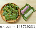 An overhead view of a bamboo basket and white and purple mochi with its leaves opened. 143719231