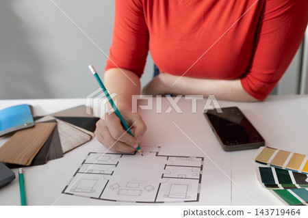 Interior designer annotating a floor plan at a design desk during home renovation planning Interior designer annotating a floor plan at a design desk during home renovation planning 143719464