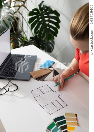 Interior designer drafts a modern room layout floor plan in a daylight studio Interior designer drafts a modern room layout floor plan in a daylight studio 143719465