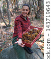 young woman foraging and picking chestnuts in an autumn forest. 143719643
