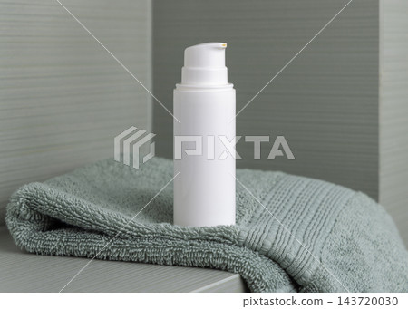 White cosmetic borttle mockup on light green towel in bathroom, unbranded packaging 143720030