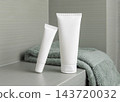 White cream tubes mockup near green terry towel in bathroom closeup, unbranded cosmetic packaging 143720032