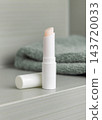 Open lip balm stick with a lid mockup in green bathroom. Herbal cosmetic product for home use 143720033