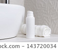 Blank cosmetic bottle mockup near white towel in beige bathroom, unbranded packaging 143720034