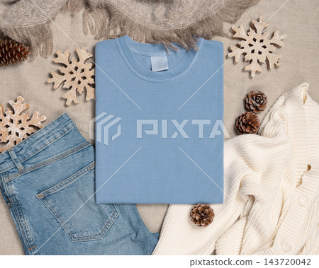Falded washed light blue t-shirt mockup near rustic Christmas decor, flat lay. Holiday template 143720042