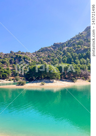 El Chorro Reservoir inland beach surrounded by rugged mountains and dramatic cliffs creates a scenic recreational landscape in Andalusia, Spain 143721496