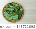 A bamboo basket of mochi placed to the left of the wood grain, viewed from directly above. 143721898
