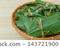 Close-up of the leaf wrapping and knot of mochi served in a bamboo basket. 143721900