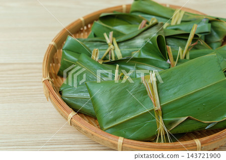 特寫:竹籃中盛裝的麻糬,葉子包裹著麻糬,打了個結。 特寫:竹籃中盛裝的麻糬,葉子包裹著麻糬,打了個結。 143721900