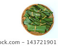 An overhead view of a bamboo basket containing mochi placed on the right side against a light-colored background. 143721901