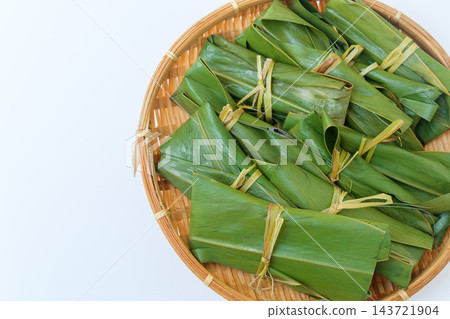 特寫鏡頭:一個竹籃和麻糬放在右側,背景是淺色的。 特寫鏡頭:一個竹籃和麻糬放在右側,背景是淺色的。 143721904