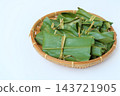 A low view of mochi wrapped in leaves in a bamboo basket 143721905