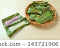 White and purple mochi wrapped in open ginger lily leaves and a bamboo basket. 143721906