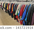 Colorful T-shirts are lined up on racks throughout the store. 143721914