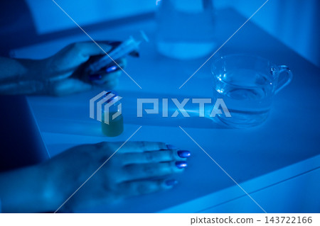 Detailed shot of hands with serum dropper. Intimate view of hands using serum dropper on counter. Closeup image capturing hands administering serum from small glass bottle Detailed shot of hands with serum dropper. Intimate view of hands using serum dropper on counter. Closeup image capturing hands administering serum from small glass bottle 143722166