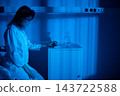 Woman scientist preparing scientific instruments carefully. Scientist woman in laboratory coat focused on finetuning analytical instrument during experiment preparation 143722588