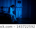 Hospital bed with weary patient. Individual resting on hospital bed illuminated by soft blue glow. Tired patient seated on hospital bed amid shadows and medical instruments 143722592