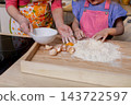 Parent and child baking together, Spending quality time bonding over baking and making memories, Joyful family moment of sharing skills while cracking eggs on rustic board 143722597