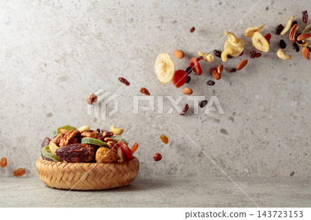 Mix of dried fruits and nuts in motion on a gray background. Mix of dried fruits and nuts in motion on a gray background. 143723153