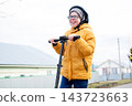 Close-up of a smiling preteen boy in helmet and glasses riding scooter outdoors in fall 143723663