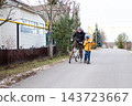 Father on bike and son on scooter traveling on empty residential asphalt road in autumn countryside 143723667