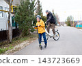 Father on bike and son on scooter traveling on empty residential asphalt road in autumn countryside 143723669