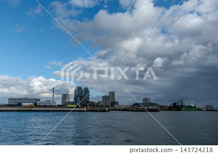 City skyline over the sea at the harbor under a cloudy sky City skyline over the sea at the harbor under a cloudy sky 143724218