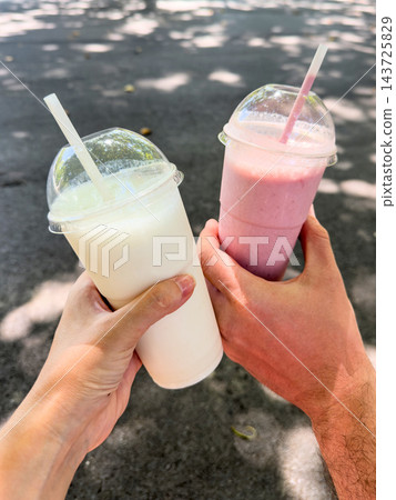 Two hands clinking a milkshake and a smoothie in Bilbao Spain Two hands clinking a milkshake and a smoothie in Bilbao Spain 143725829