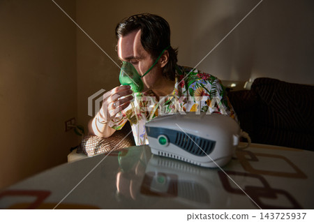 Man using a nebulizer and oxygen mask at home for breathing therapy 143725937