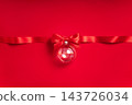 Minimalist Christmas and New Year background with glass ornament, red satin bow and ribbon, top view flat lay. Festive holiday concept with copy space for greeting cards, gifts and advertising 143726034