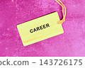 A wooden tag marked career rests on a pink surface, representing work and job planning in a studio setting 143726175
