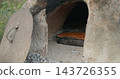 Traditional bread baking in outdoor clay oven 143726355