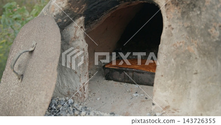 Traditional bread baking in outdoor clay oven Traditional bread baking in outdoor clay oven 143726355