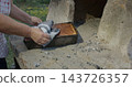 Woman baking homemade pie in traditional clay oven 143726357