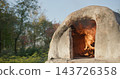 Traditional wood-fired clay oven burning outdoors 143726358