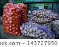 Organic Farming Concept with Potatoes and Onions in Vintage Burlap Bag Against Rustic Mud 143727950