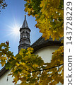 Autumn Church Steeple Framed by Golden Leaves Under Bright Sun and Clear Blue Sky 143728229