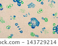 Knitted light beige fabric with a children's print, macro photo. 143729214